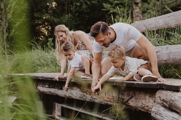 Eine vierköpfige Familie schaut gespannt von einer kleinen Holzbrücke hinab. Eine echte Momentaufnahme, welche die Fotografin für Family Shootings hier eingefangen hat.