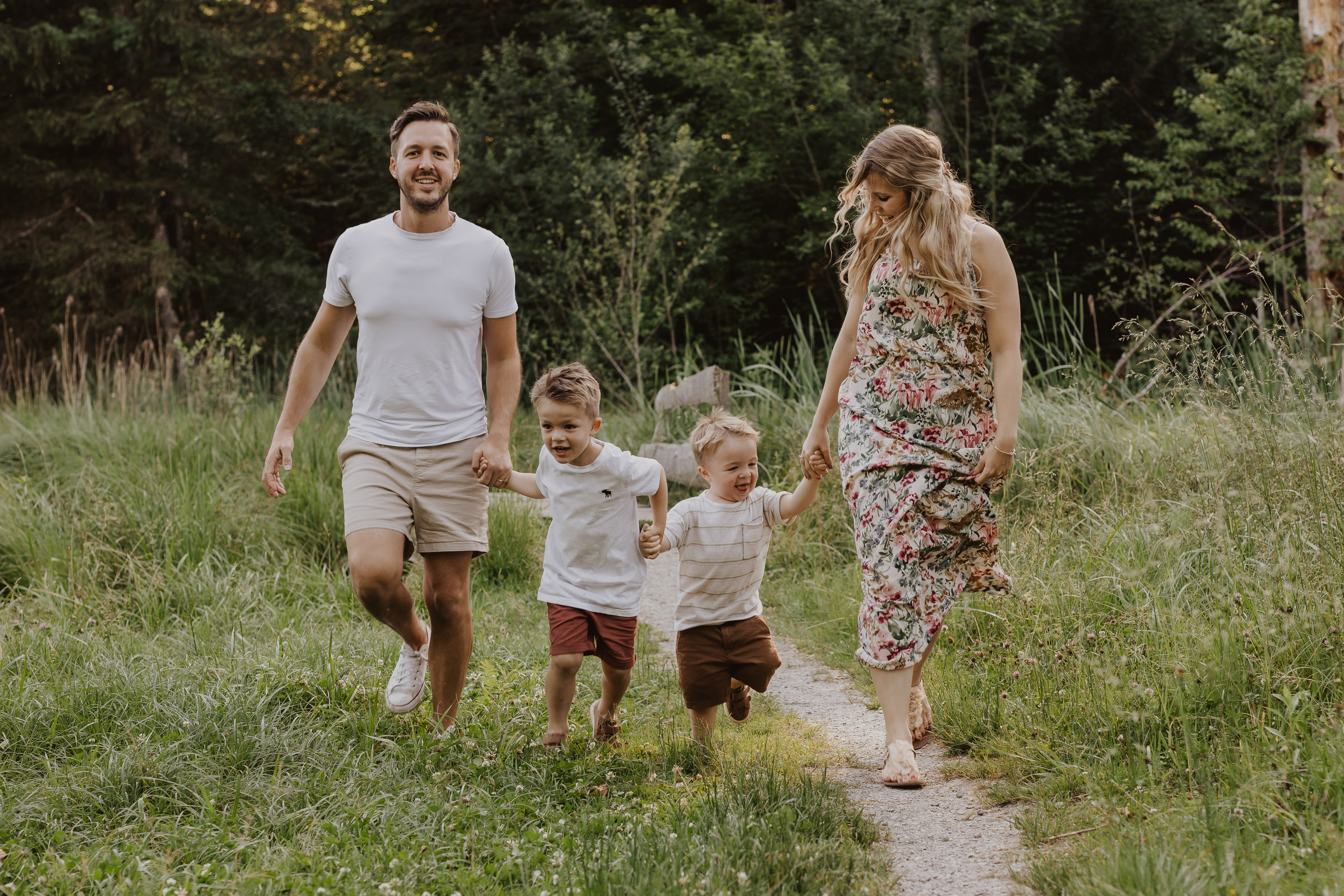 Eien vierköpfige Familie rennt Hand in Hand über einen Naturweg der Fotografin entgegen. Die Kinder lachen und freuen sich. Eine ungestellte Aufnahme, natürliche Emotionen eingefangen von Natascha Ender, der Fotografin aus dem Aargau für Famileinshootings.
