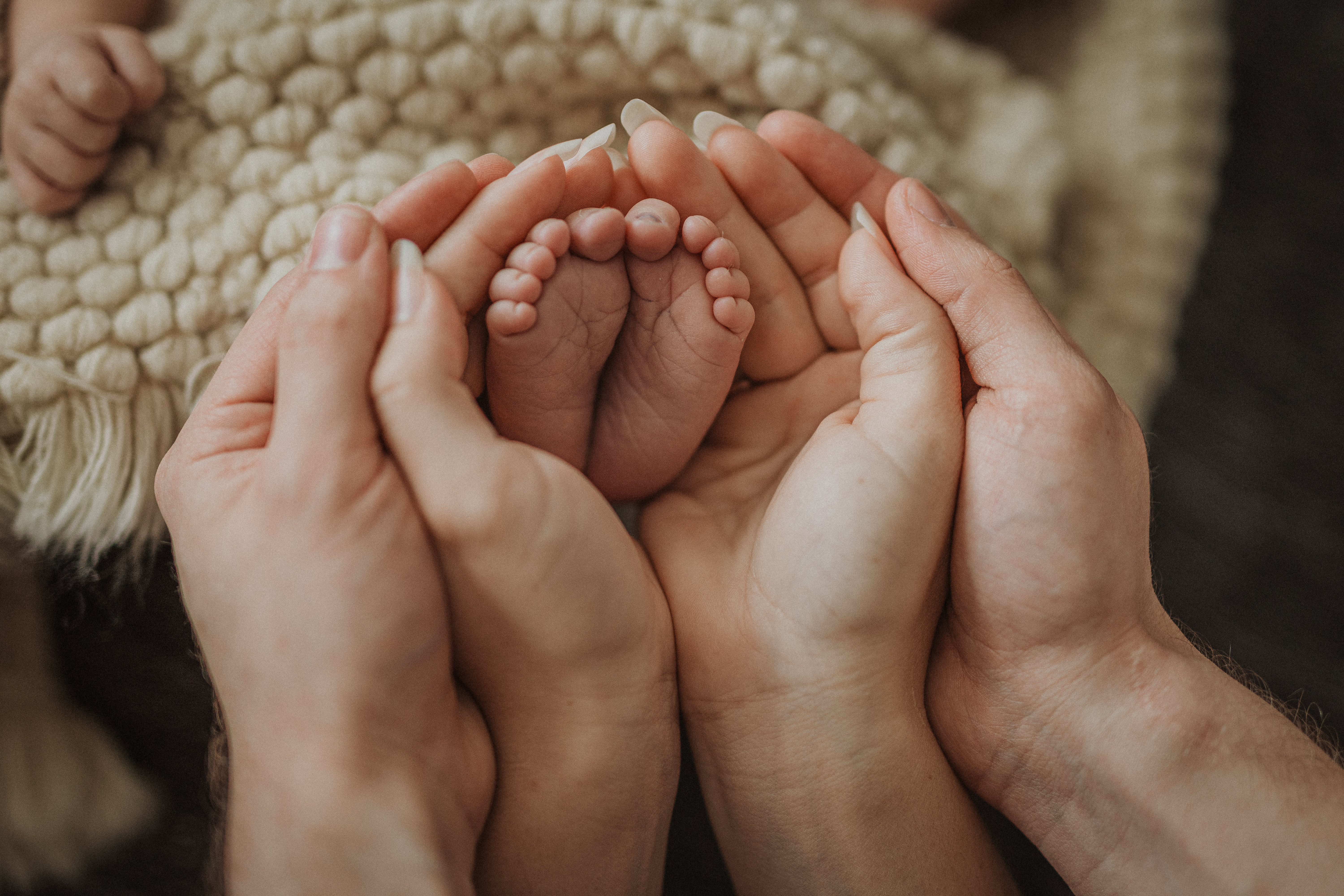 Die Füsse eines kleinen Babys, welche von den Händen der Eltern umschlossen werden. Eine hinreissende Nahaufnahme, welche die Verbundenheit der frischgebackenen Familie aufzeigt und Emotionen versprüht. Sehr schön eingefangen von der Newborn Fotografin während des Fotoshootings